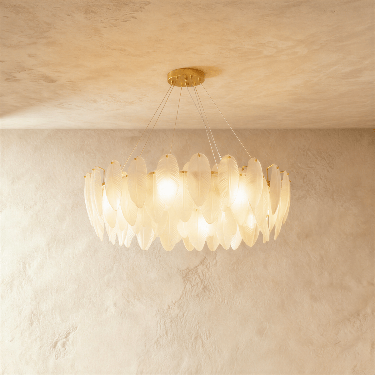 Modern feather chandelier with brass finish, suspended in elegant living room with gray upholstered seating and sheer curtain