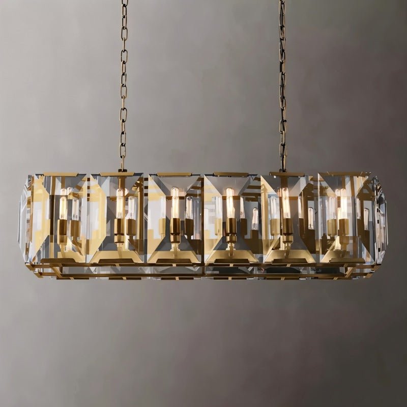Brass linear chandelier with geometric crystal panels suspended from chains against a neutral gray wall.