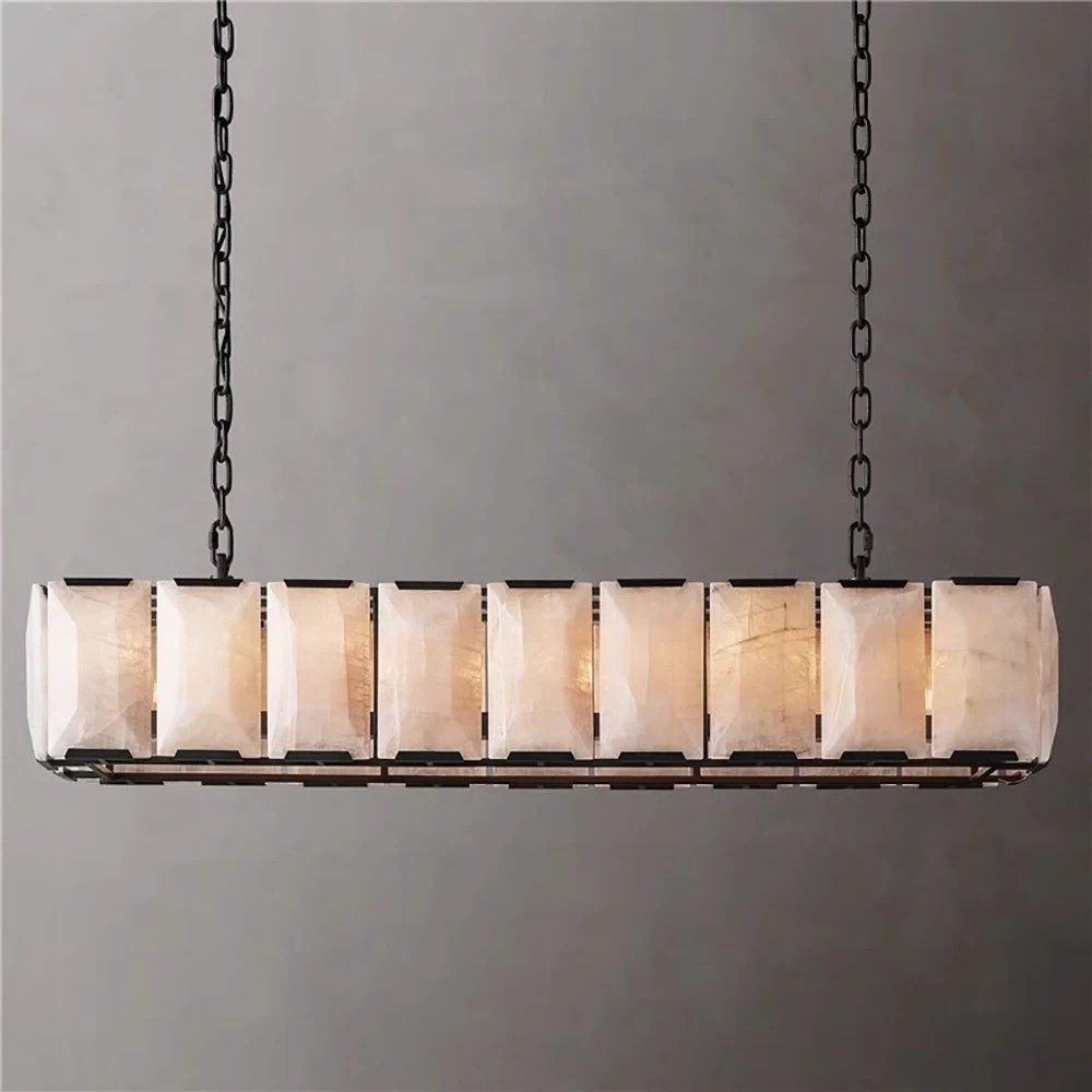 Linear chandelier with dark bronze frame and segmented alabaster shades, suspended by chains against gray background.