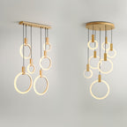 Modern pendant chandelier with warm brass finish and illuminated ring-shaped LED lights suspended from wooden dowels against white background.